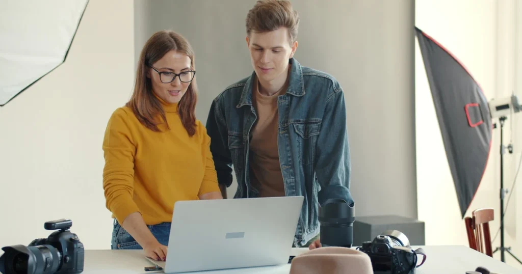 Osoba sedí u stolu s notebookem a studiuje portfolio agentury, v přirozeném osvětlení domácího interiéru
