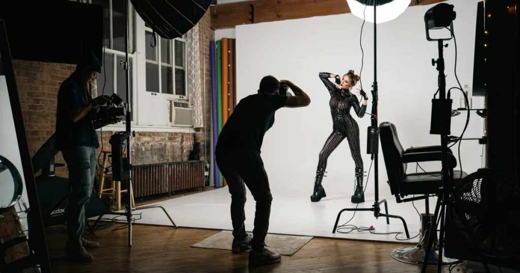 Mladá modelka si prohlíží fotografové portfolio a mood boards na pracovním stole v jednoduchém fotostudiu