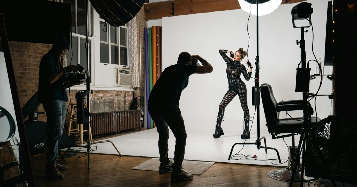 Mladá modelka si prohlíží fotografové portfolio a mood boards na pracovním stole v jednoduchém fotostudiu