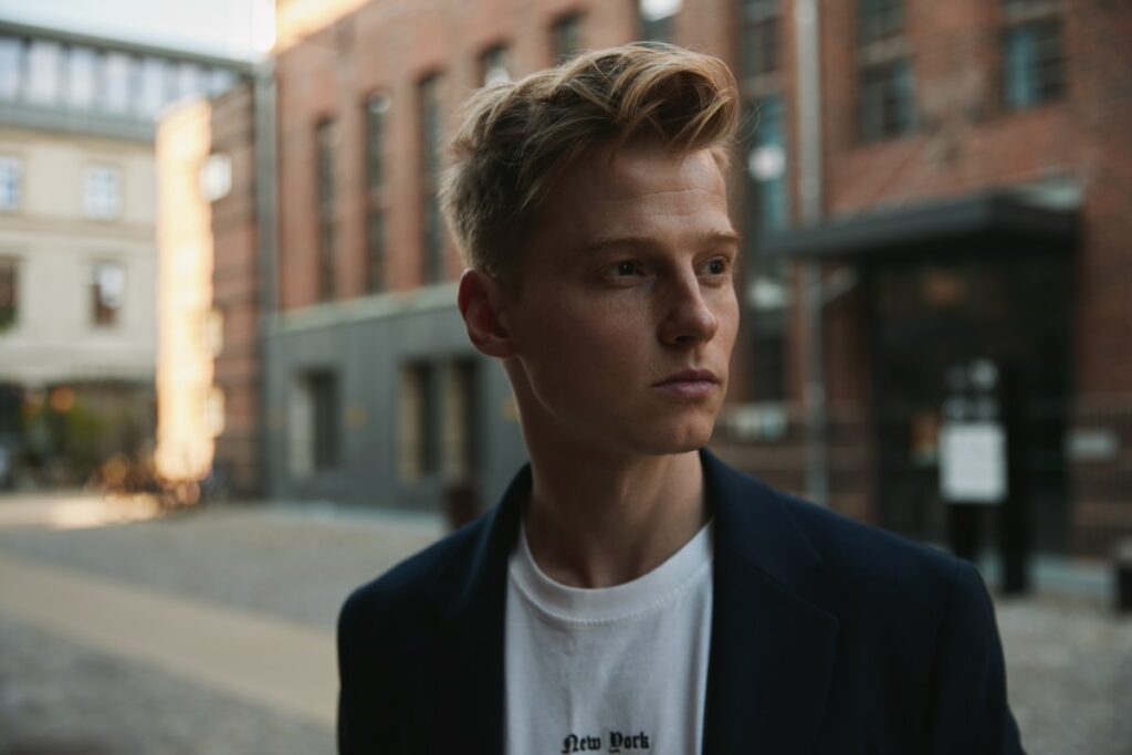 Muž v modelingové agentury si prohlíží své fotografické portfolio na tabletu, seděl v čekárně s plakáty v pozadí